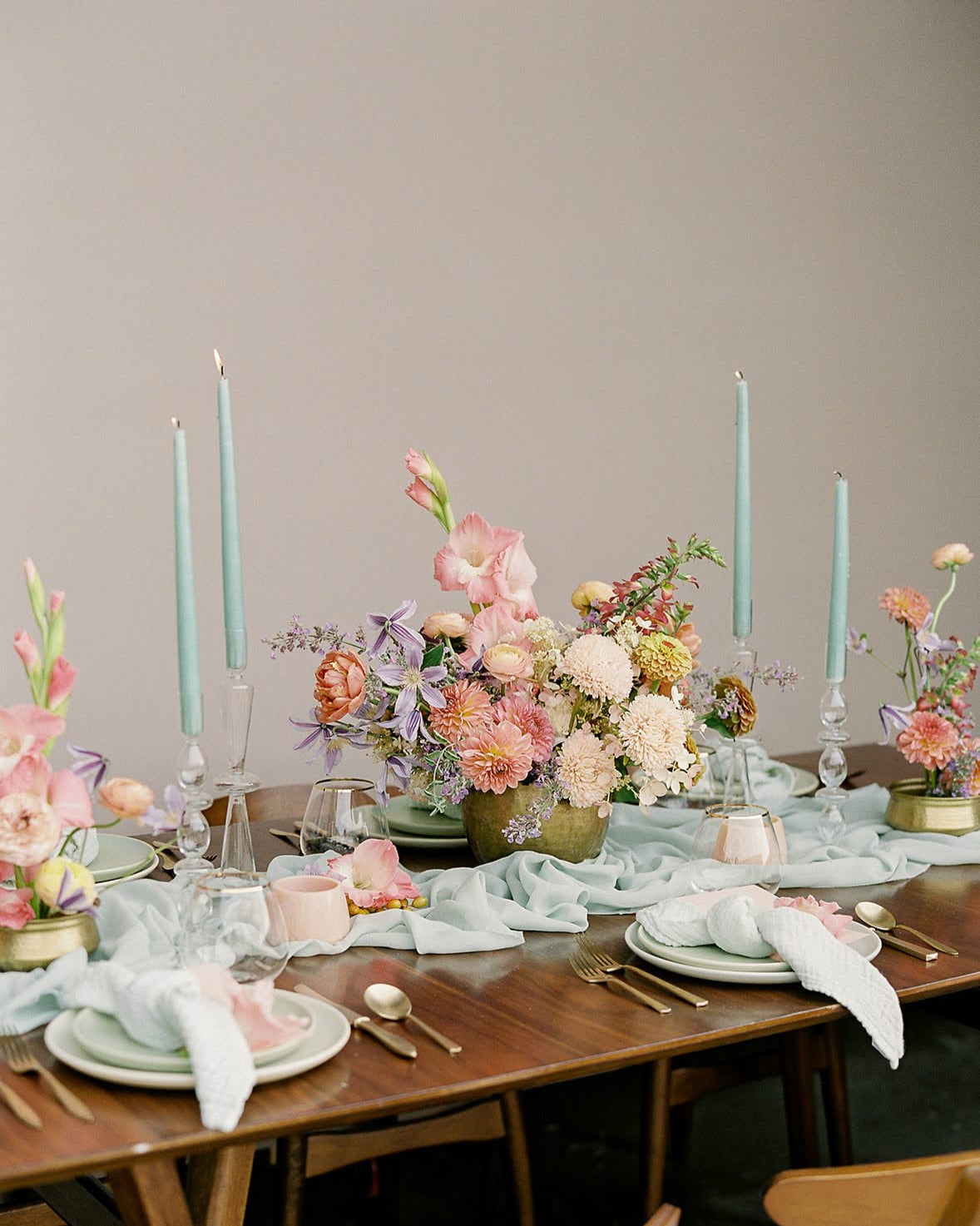 Elegant table setting with floral centerpieces, candles, and cutlery on a wooden table with borrowed BLU's Organic Cotton Napkin in Sage.